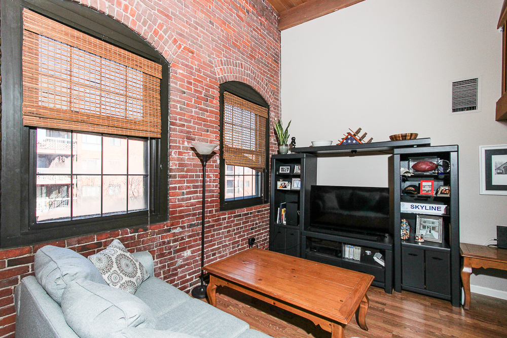 Living room with brick wall and two large windows